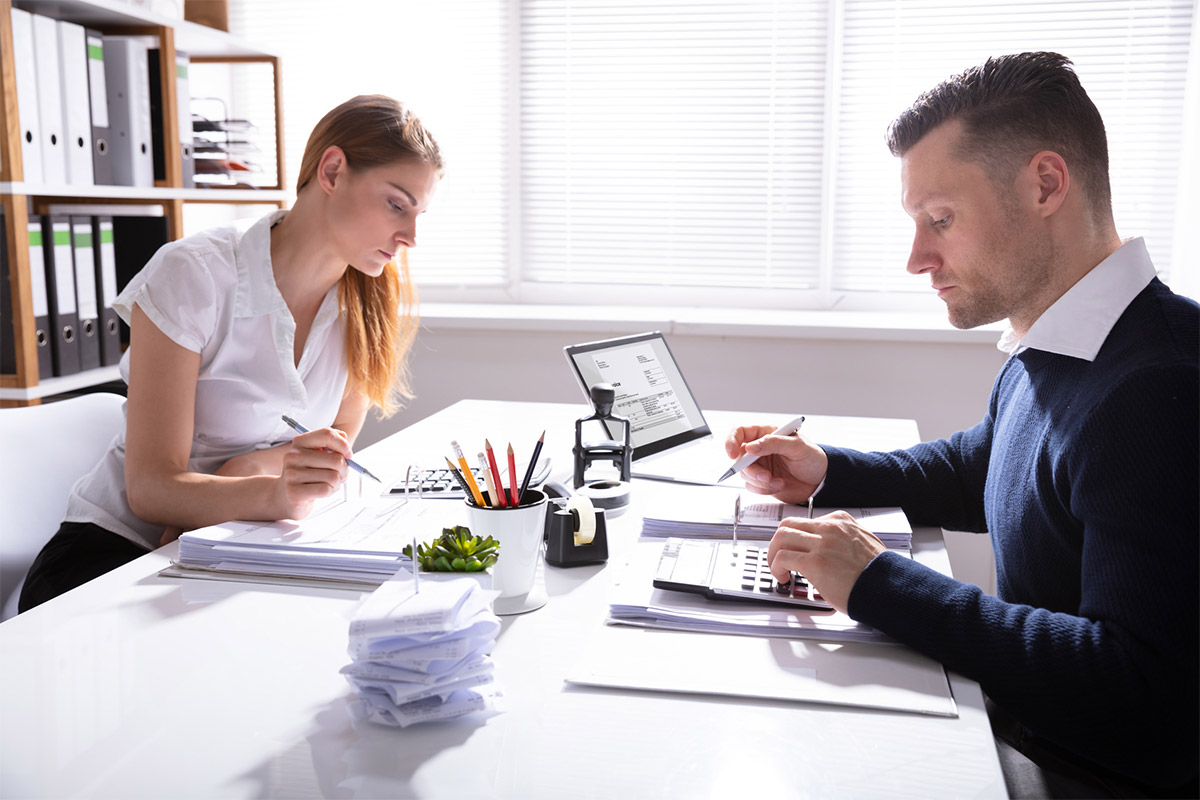 Young Couple At Desk Reviewing Paperwork